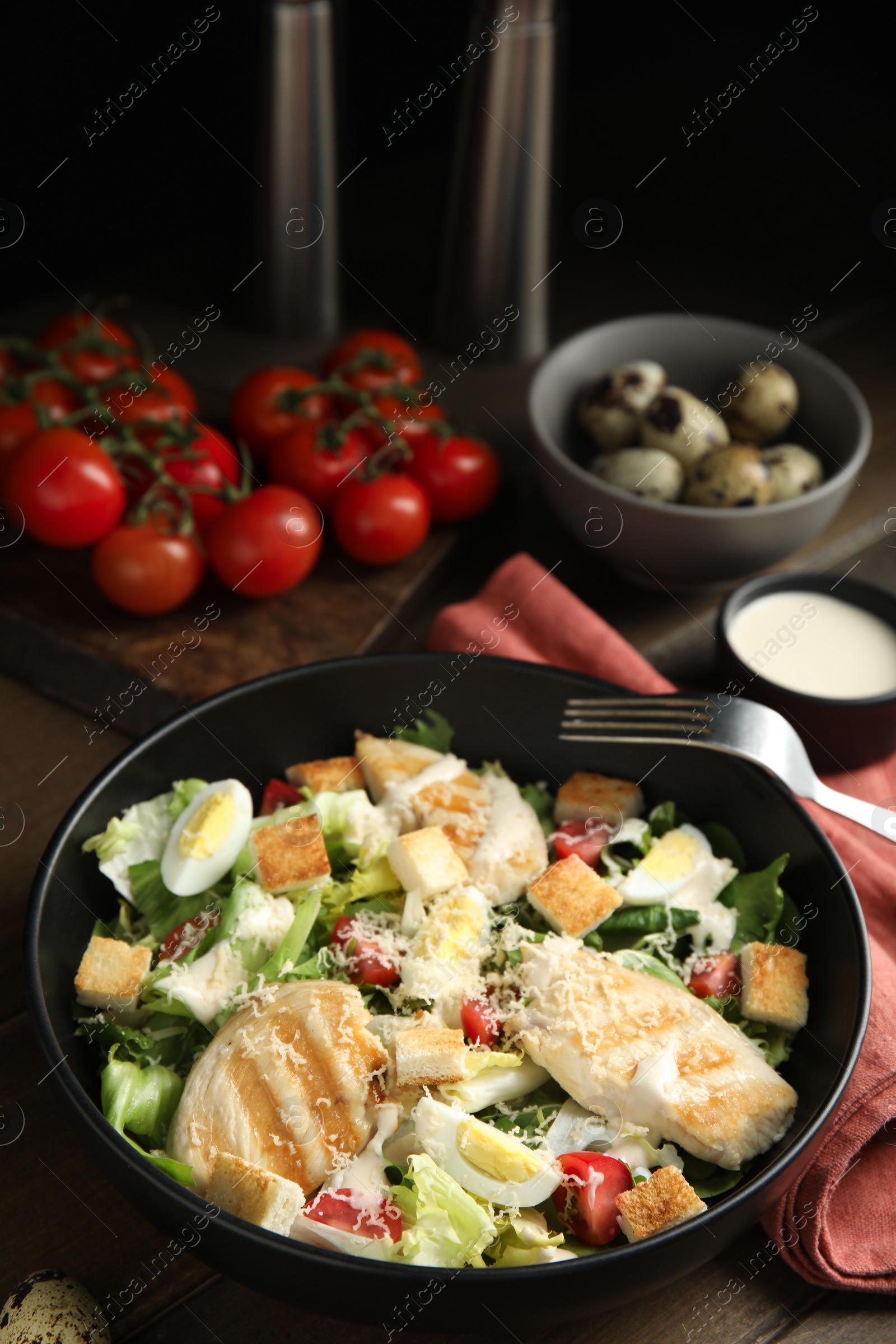 Photo of Delicious Caesar salad in bowl on wooden table