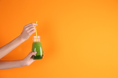 Photo of Young woman holding bottle of healthy smoothie on color background