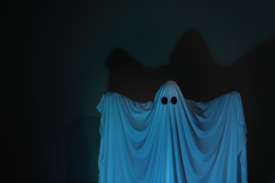 Creepy ghost. Woman covered with sheet on dark background, space for text