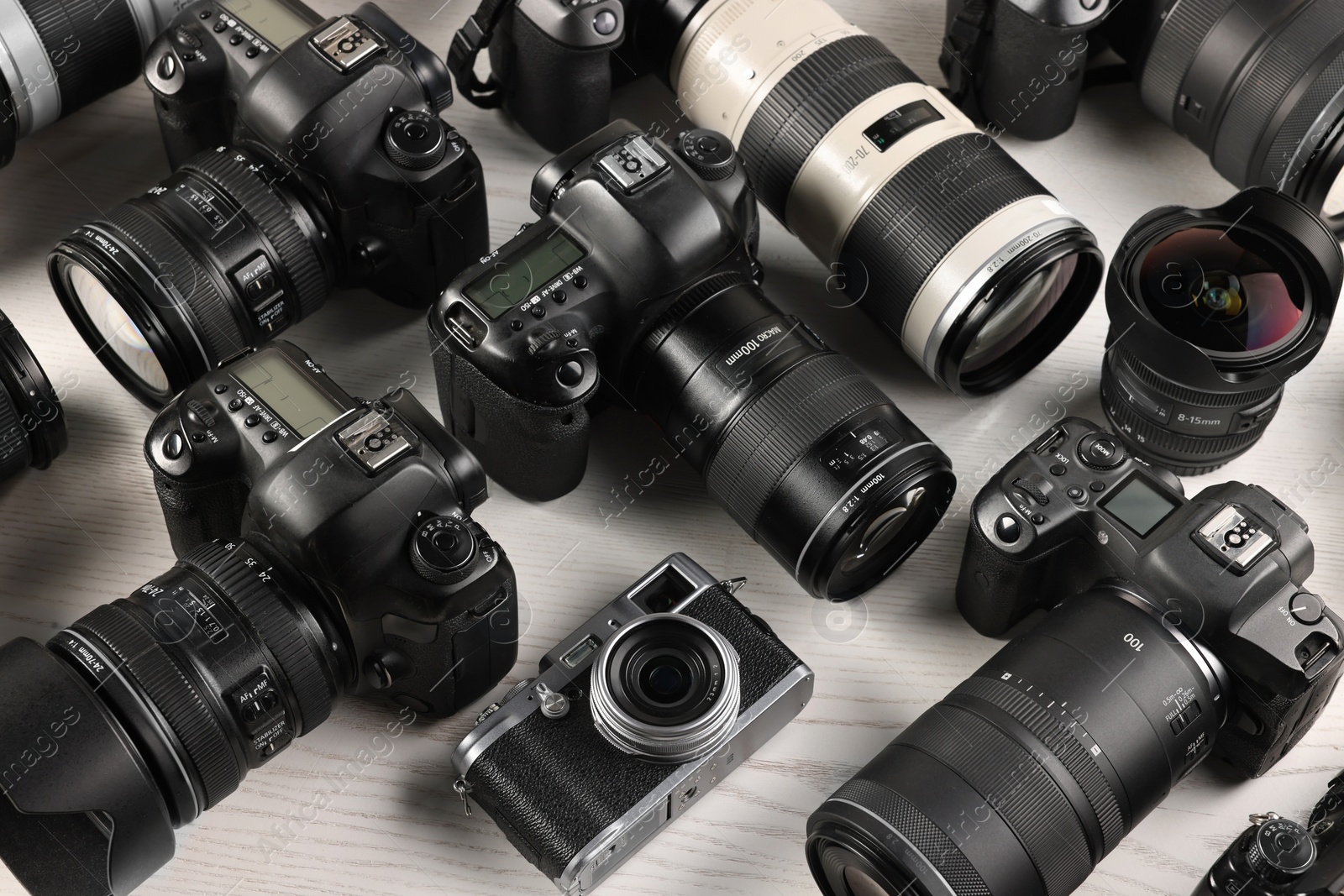 Photo of Modern cameras on white wooden table, closeup