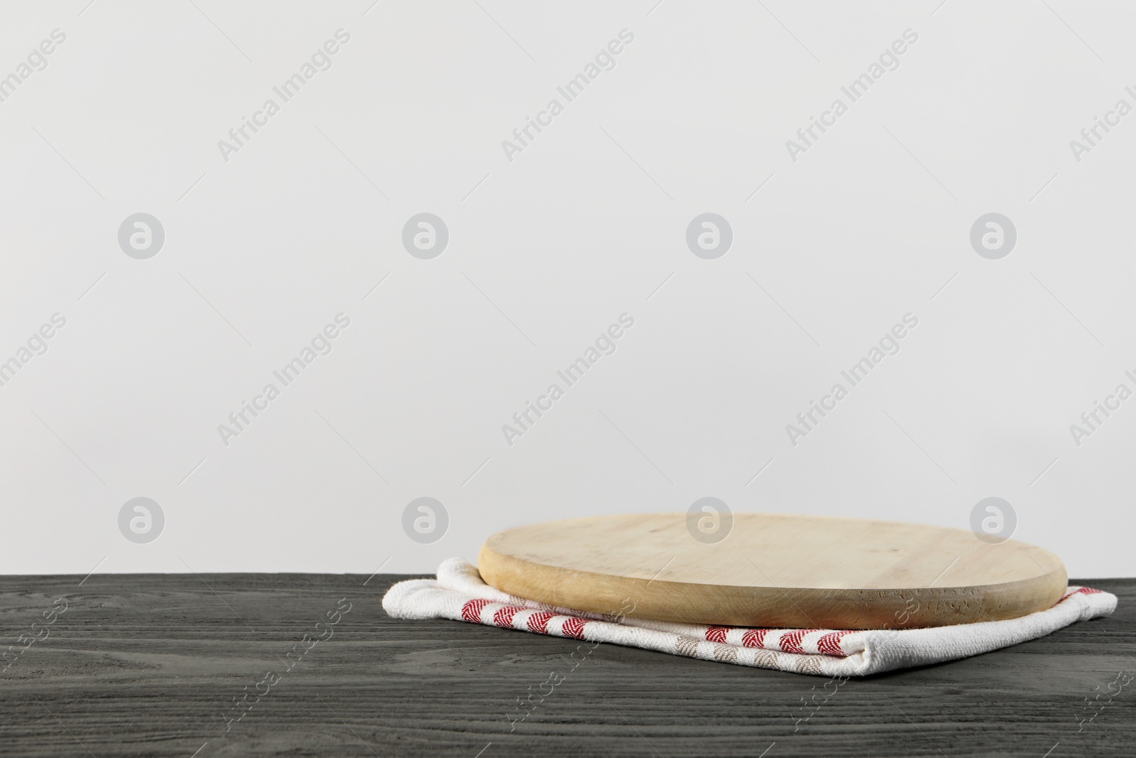 Photo of Empty board and towel on grey wooden table. Space for text