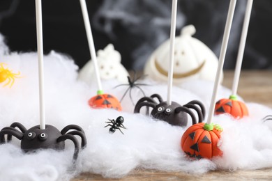 Different Halloween themed cake pops on wooden table, closeup