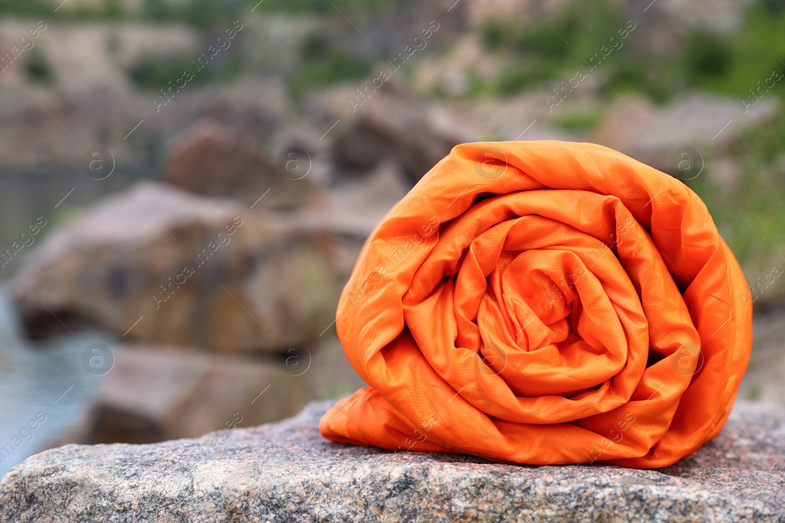 Photo of Folded sleeping bag on sunny day outdoors, closeup. Space for text