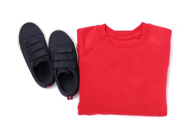 Photo of Red warm sweater and sport shoes on white background, top view