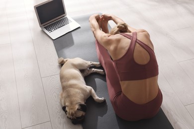Photo of Woman with dog following online yoga class at home, above view