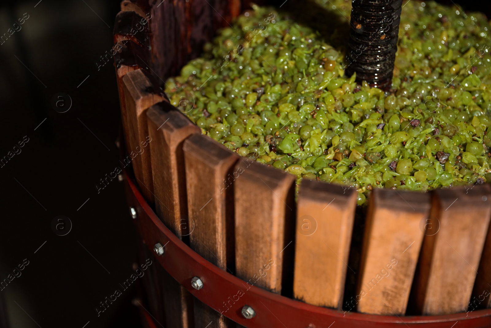 Photo of Wooden wine press with grape must indoors, closeup