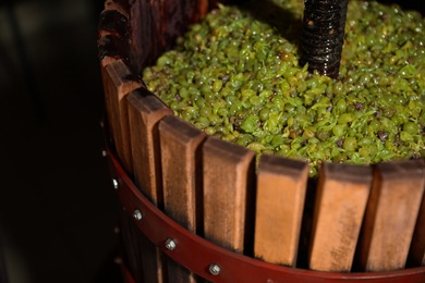 Photo of Wooden wine press with grape must indoors, closeup