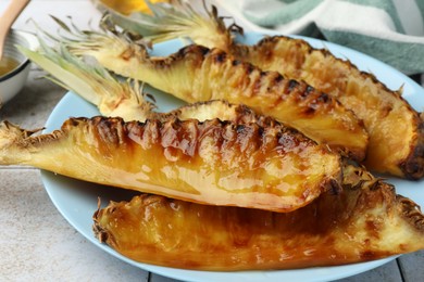 Tasty grilled pineapples on light gray table, closeup