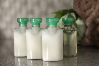 Photo of Mini bottles of cosmetic products on grey textured table