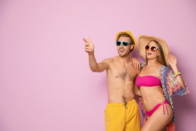 Photo of Happy young couple in beachwear on color background. Space for text