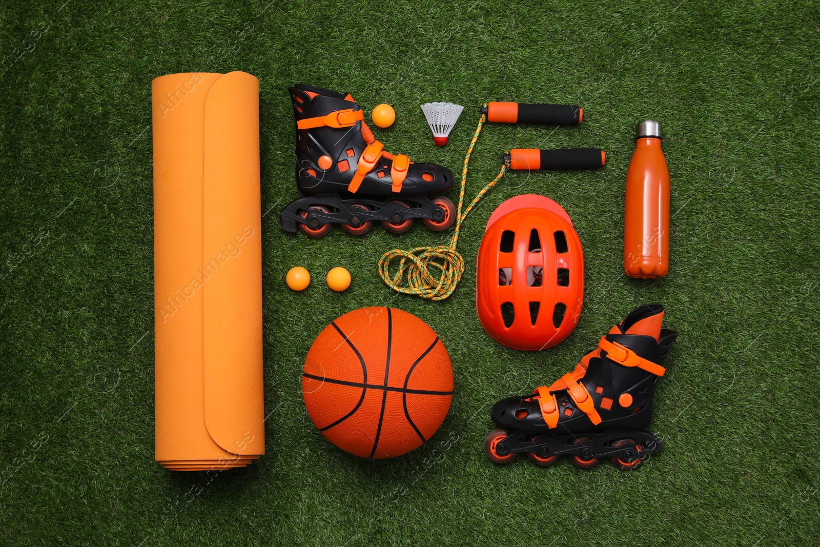 Photo of Different sport equipment on green grass, flat lay