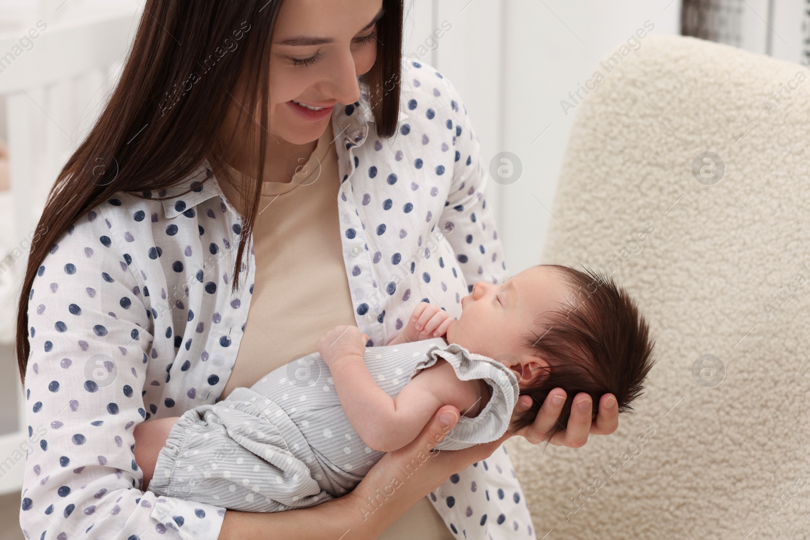 Photo of Mother with her sleeping newborn baby indoors