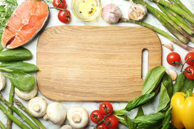 Photo of Flat lay composition with asparagus, products and wooden board on white marble table, space for text