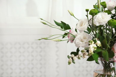 Photo of Glass vase with bouquet of beautiful flowers on blurred background. Space for text