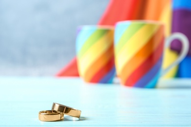 Photo of Wedding rings, rainbow cups and flag on background. Gay marriage