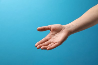 Woman holding something in hand on light blue background, closeup