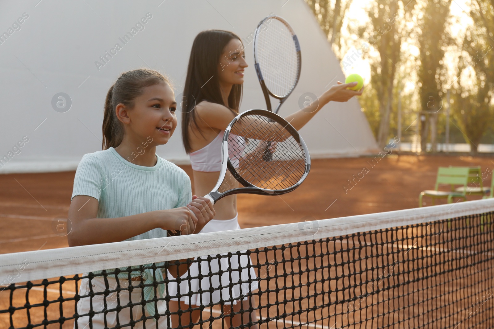 Photo of Mother with her daughter playing tennis on court