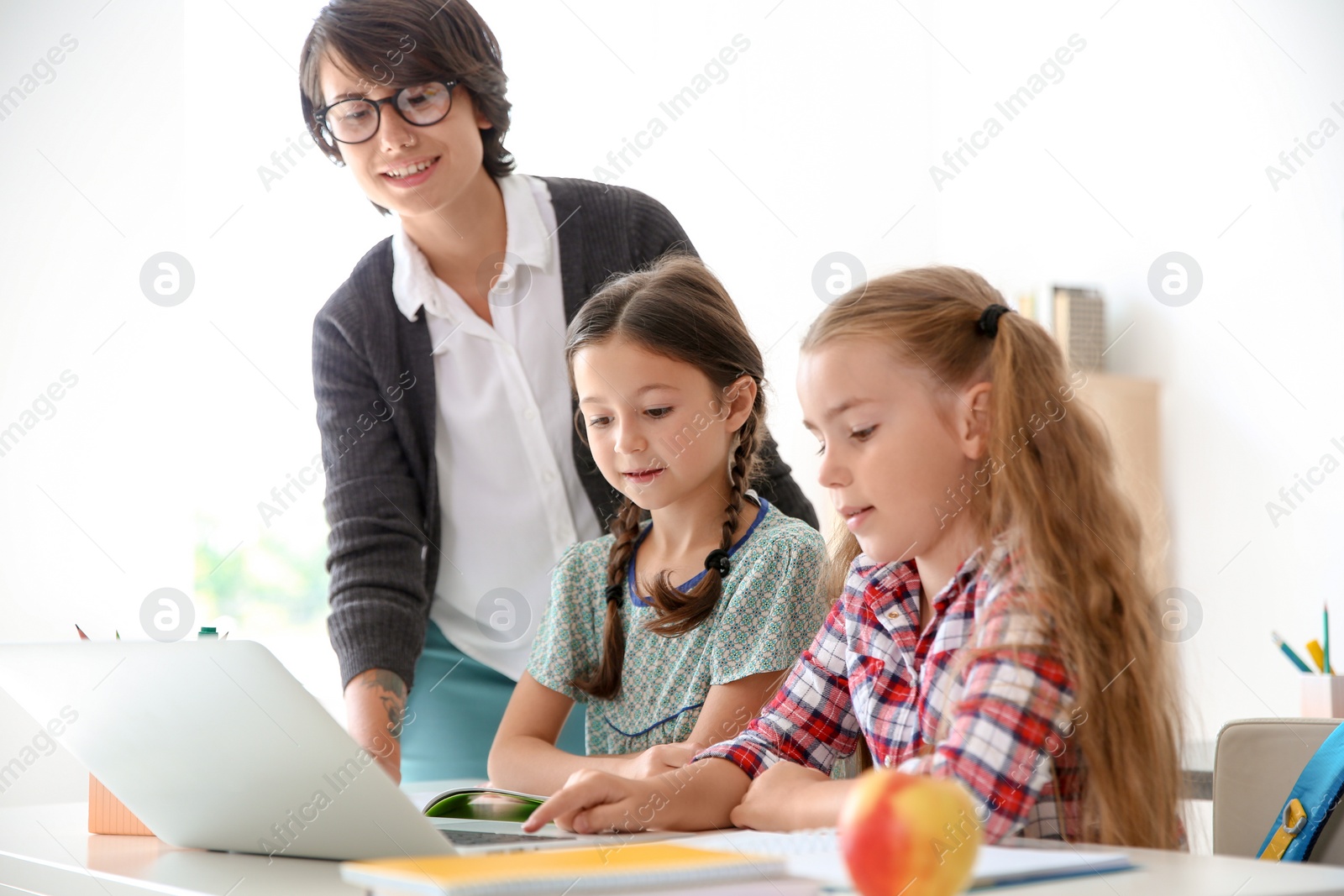 Photo of Female teacher helping children with assignment at school