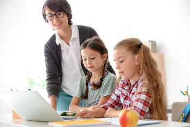 Female teacher helping children with assignment at school