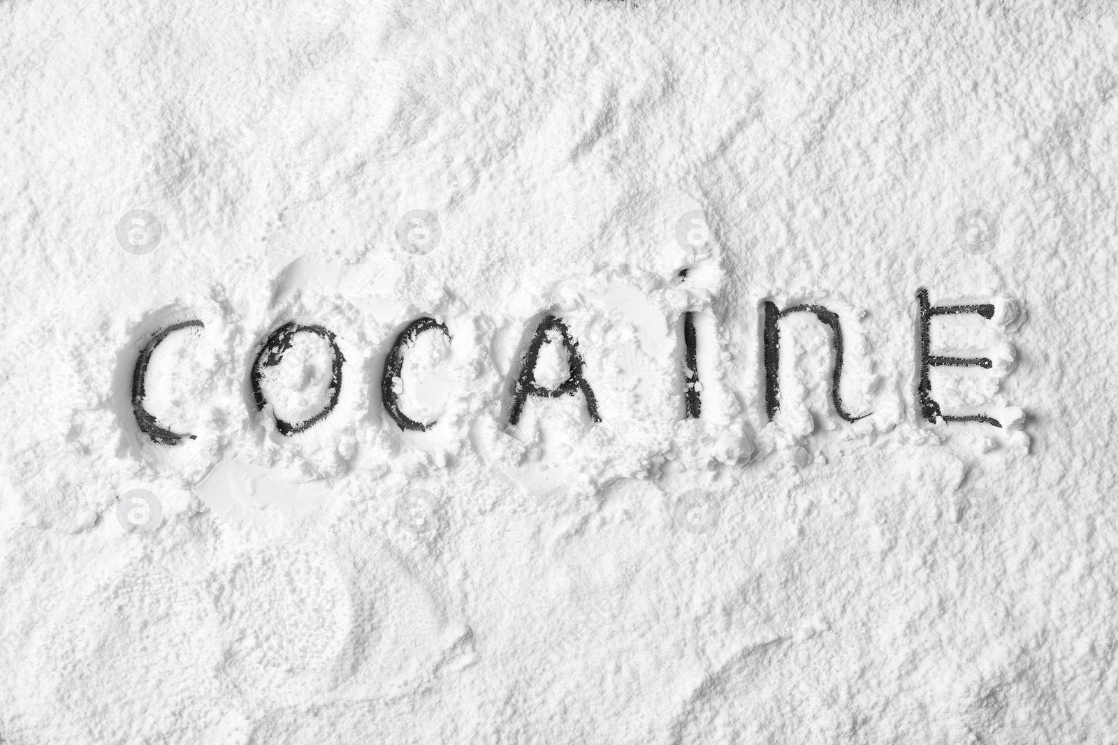 Photo of Word Cocaine written on white powder as background, top view