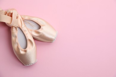 Photo of Ballet shoes. Elegant pointes on pink background, top view. Space for text