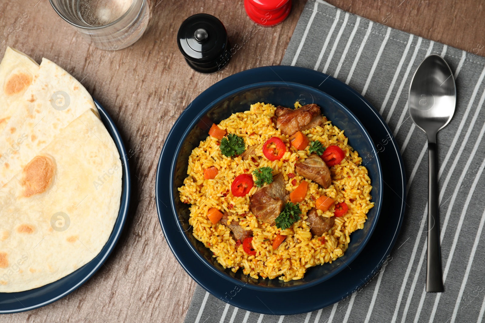 Photo of Flat lay composition with plate of rice pilaf and meat on wooden background