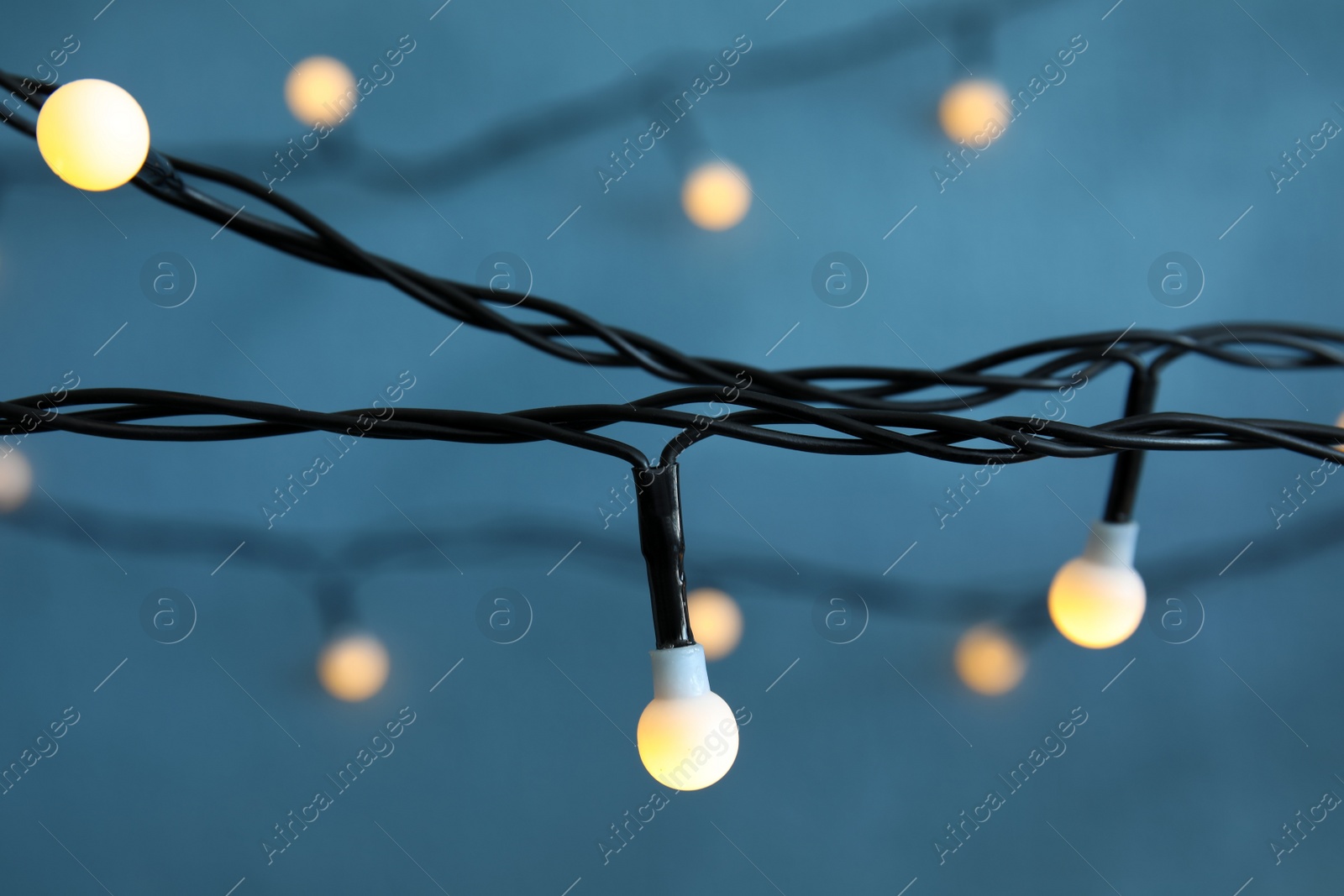 Photo of Beautiful Christmas lights on color background, closeup