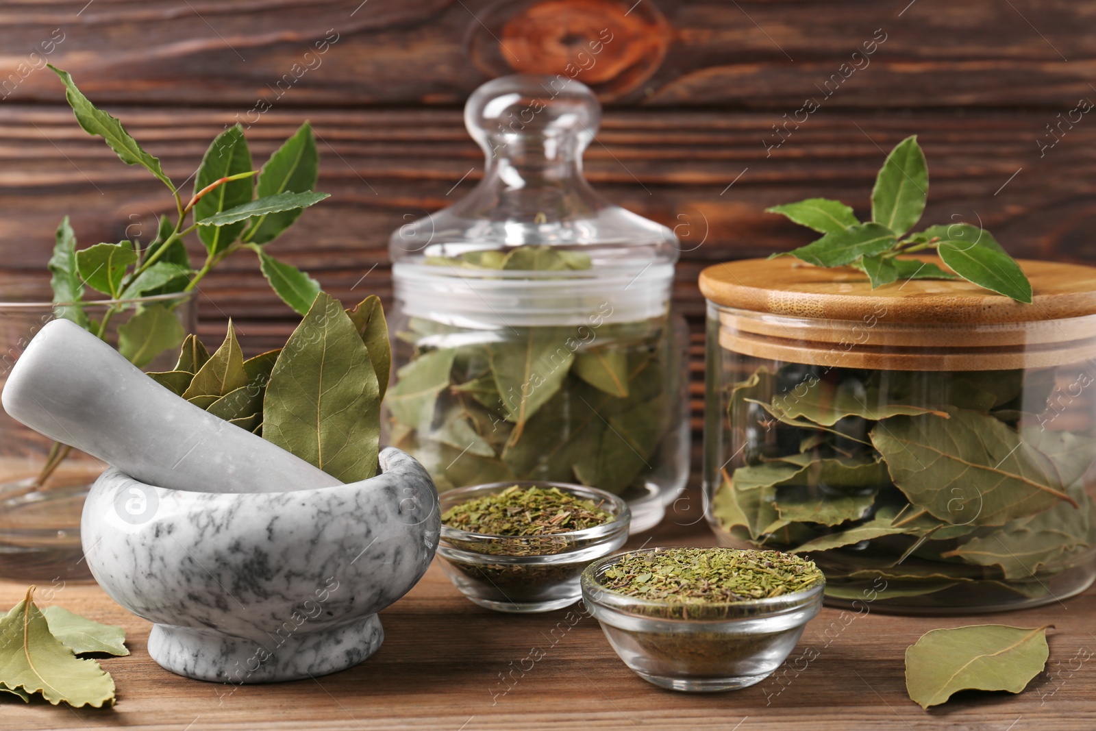 Photo of Whole and ground aromatic bay leaves on wooden table