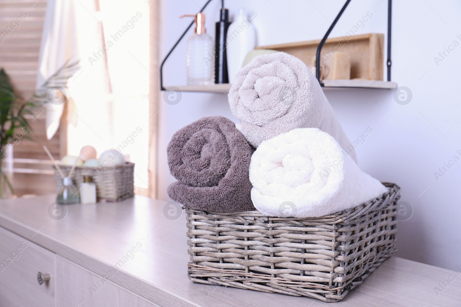 Photo of Basket with rolled fresh towels on table in bathroom. Space for text