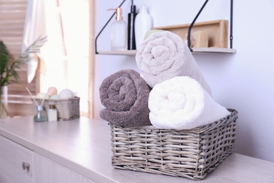 Basket with rolled fresh towels on table in bathroom. Space for text