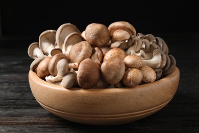 Different fresh wild mushrooms in bowl on wooden table