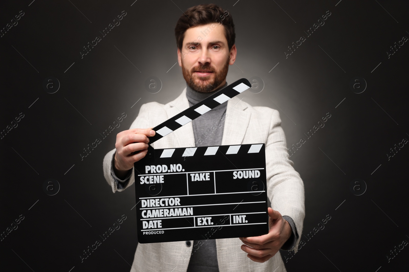 Photo of Adult actor holding clapperboard on black background