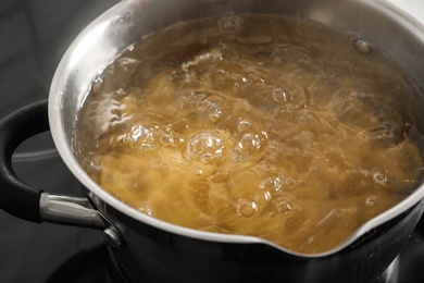 Photo of Cooking pasta in pot on stove, closeup view