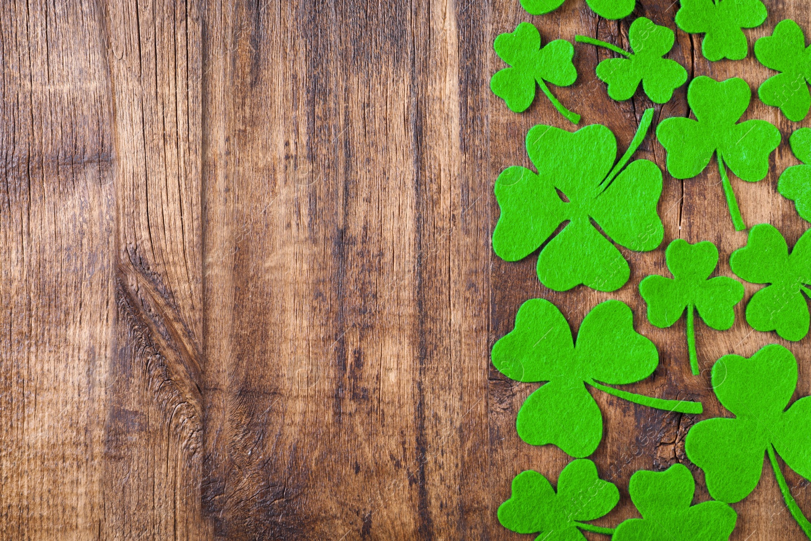 Photo of Flat lay composition with clover leaves on wooden table, space for text. St. Patrick's Day celebration