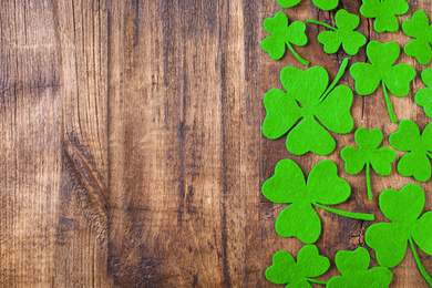 Photo of Flat lay composition with clover leaves on wooden table, space for text. St. Patrick's Day celebration