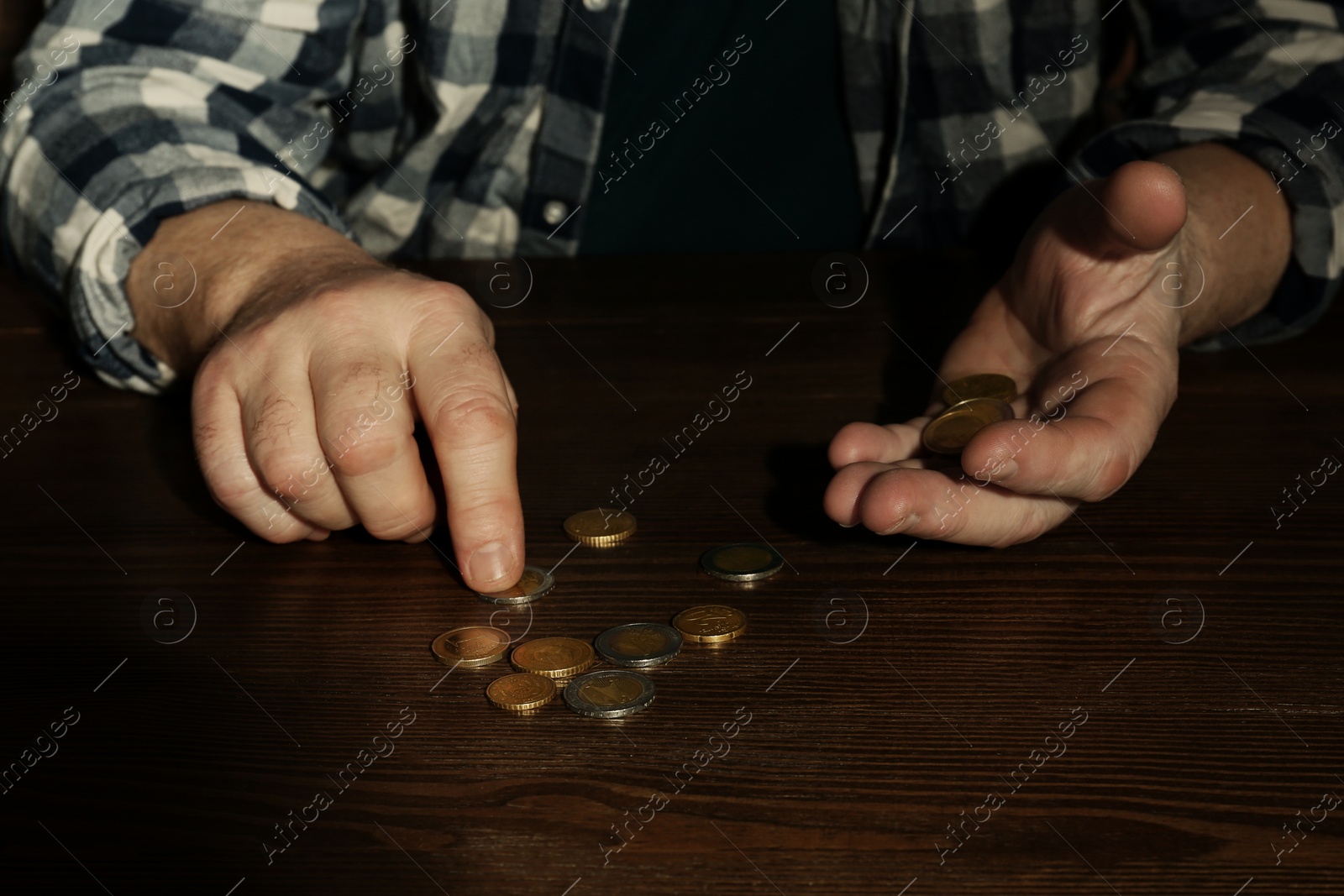 Photo of Poor senior man counting coins at table, closeup