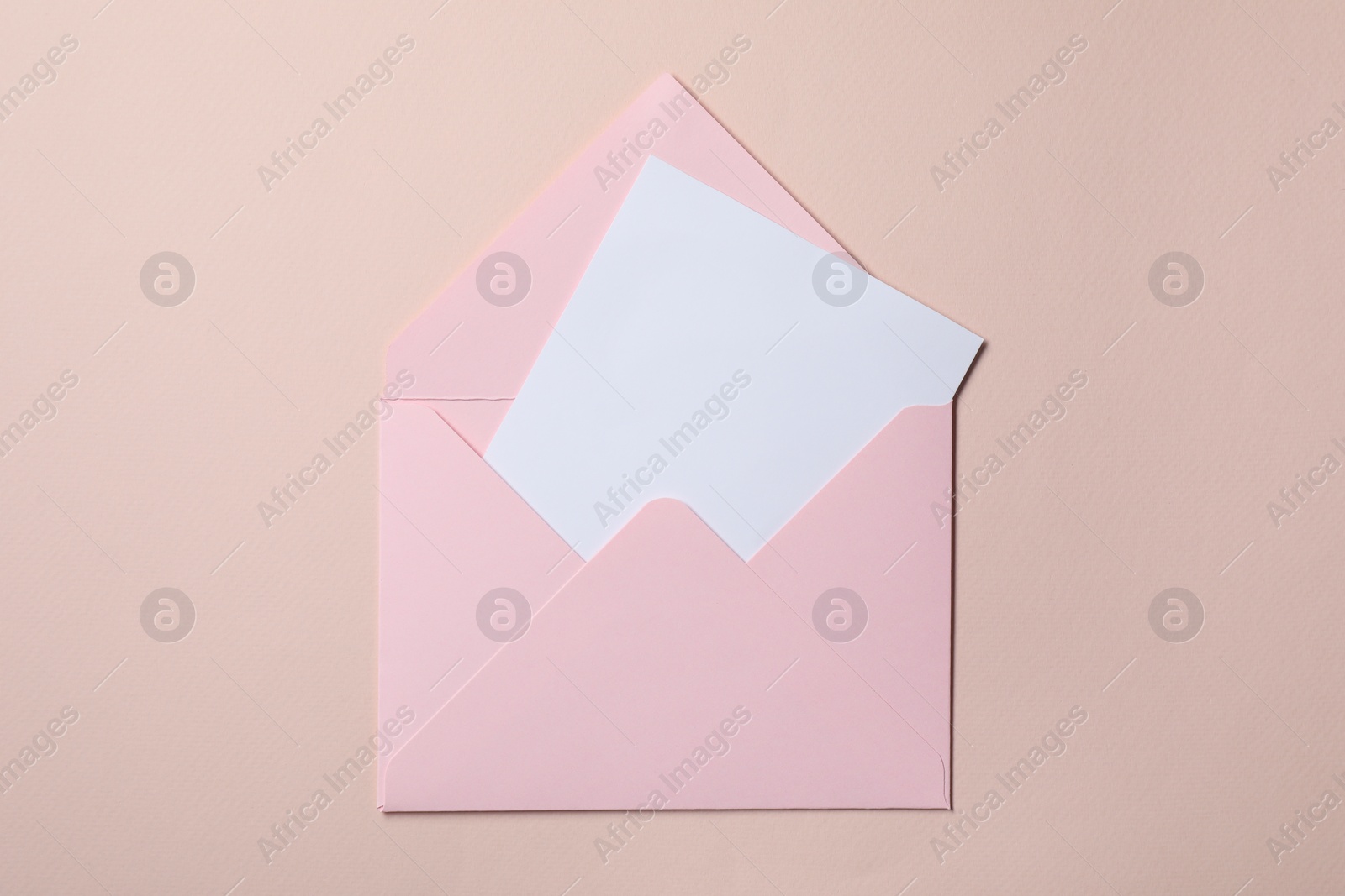 Photo of Letter envelope with card on beige background, top view