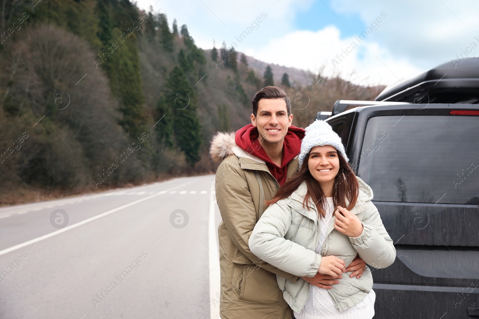Photo of Happy couple near car on road. Winter vacation