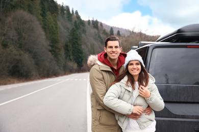 Happy couple near car on road. Winter vacation