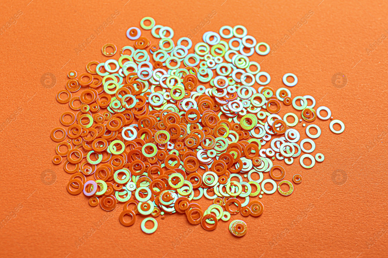 Photo of Pile of shiny bright glitter on orange background