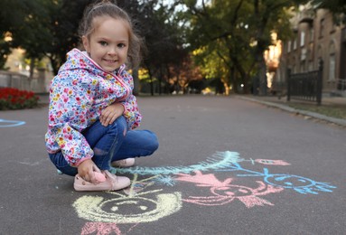 Photo of Child drawing family with chalk on asphalt