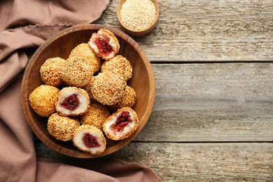 Delicious sesame balls with red bean paste on wooden table, top view. Space for text