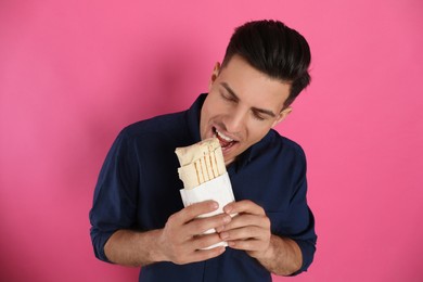 Photo of Man eating delicious shawarma on pink background