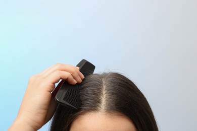 Photo of Woman with comb and dandruff in her dark hair on color background, closeup. Space for text