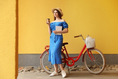 Woman with modern color bicycle near wall outside