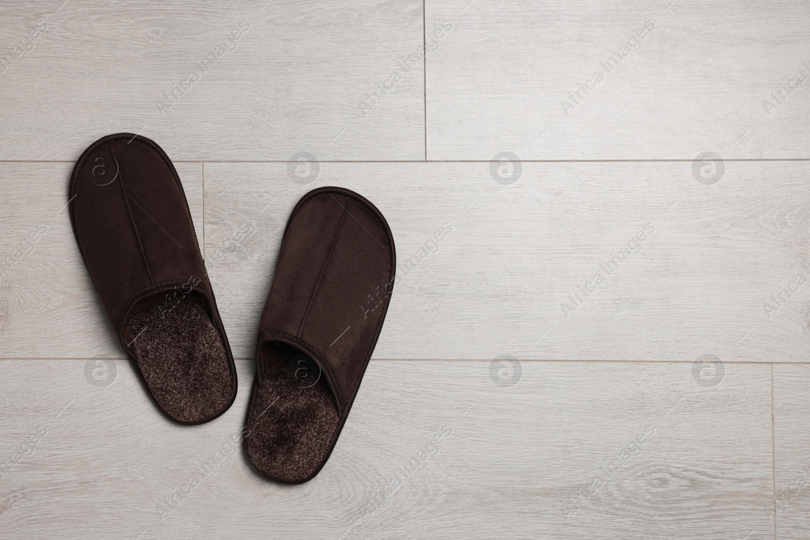 Photo of Pair of brown slippers on wooden floor, top view. Space for text