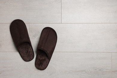 Pair of brown slippers on wooden floor, top view. Space for text