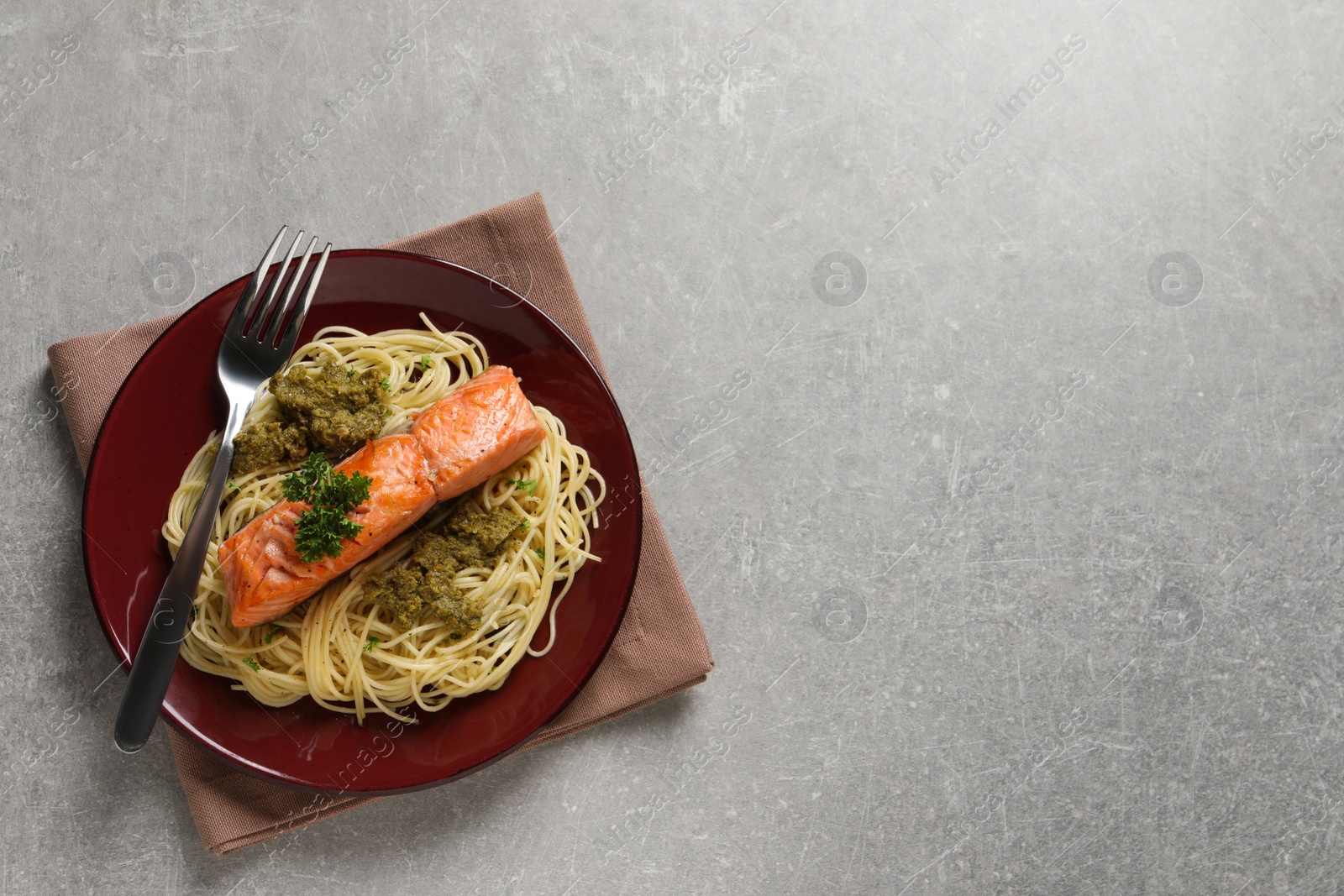 Photo of Delicious spaghetti with salmon and pesto sauce on light grey table, top view. Space for text