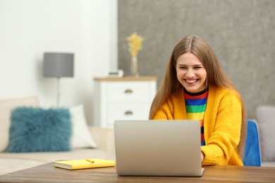 Happy young woman playing online lottery using laptop at home