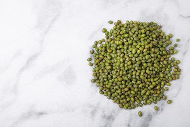 Photo of Pile of green mung beans on white marble table, top view. Space for text